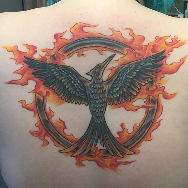 Book-inspired tattoo of a mockingbird with flames, ideal for bookworms.