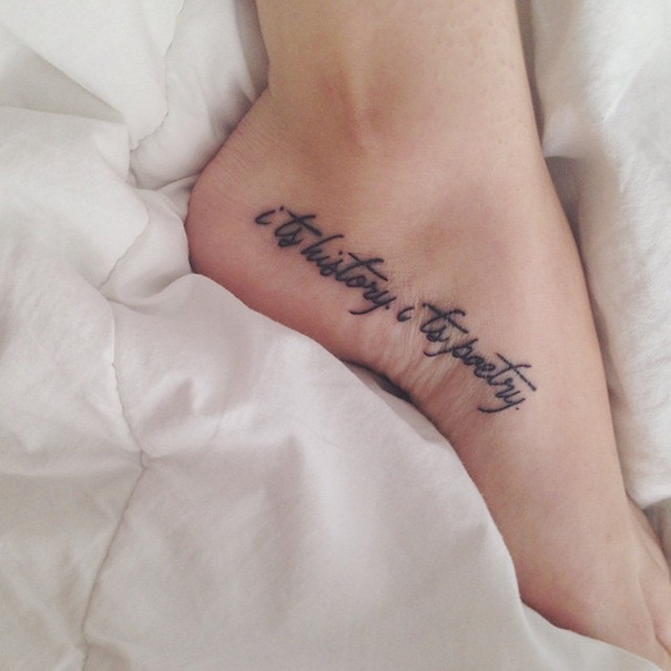 Tattoo on foot reading "it's history, it's poetry," inspired by a book quote.