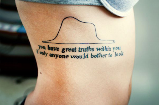 Book-inspired tattoo with a hat and quote for bookworms.