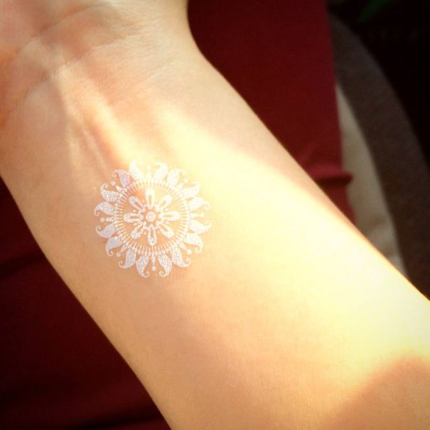 White henna-inspired tattoo on wrist, resembling elegant lace design.