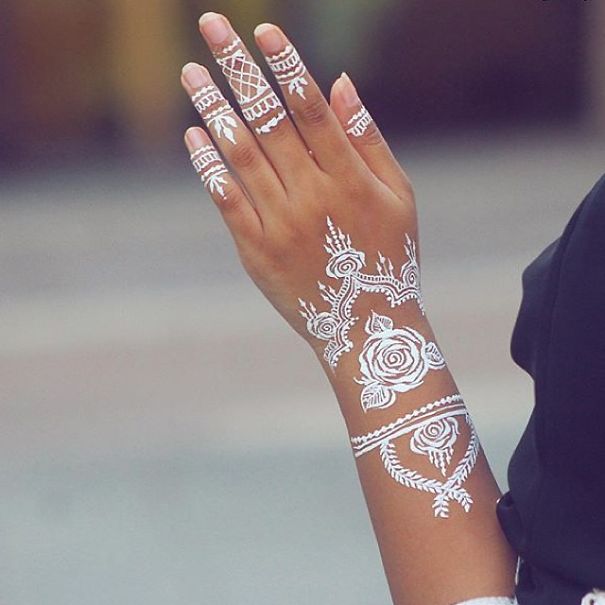 White henna-inspired tattoo on a hand, resembling elegant lace patterns.