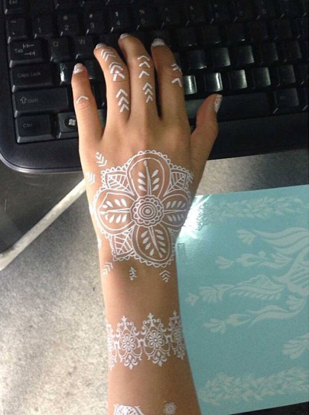 White henna-inspired tattoo on a hand, designed like elegant lace, next to a keyboard.