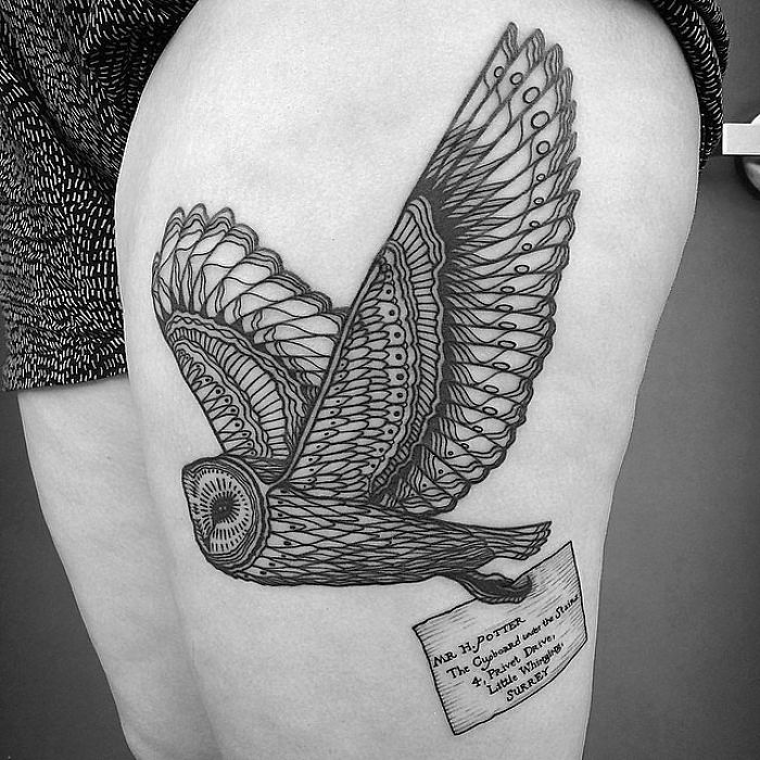 Harry Potter tattoo of a detailed owl carrying a letter on a person's thigh.