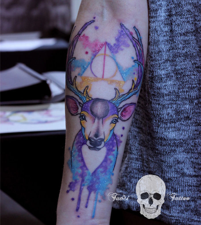 Colorful Harry Potter tattoo featuring a watercolor-style stag with antlers and the Deathly Hallows symbol.