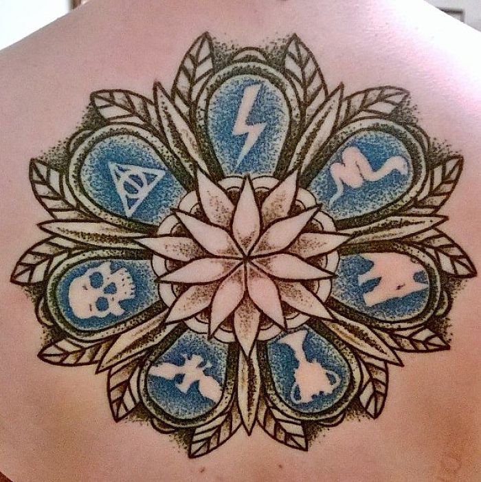 Intricate Harry Potter tattoo featuring iconic symbols in a circular pattern on a person's back.