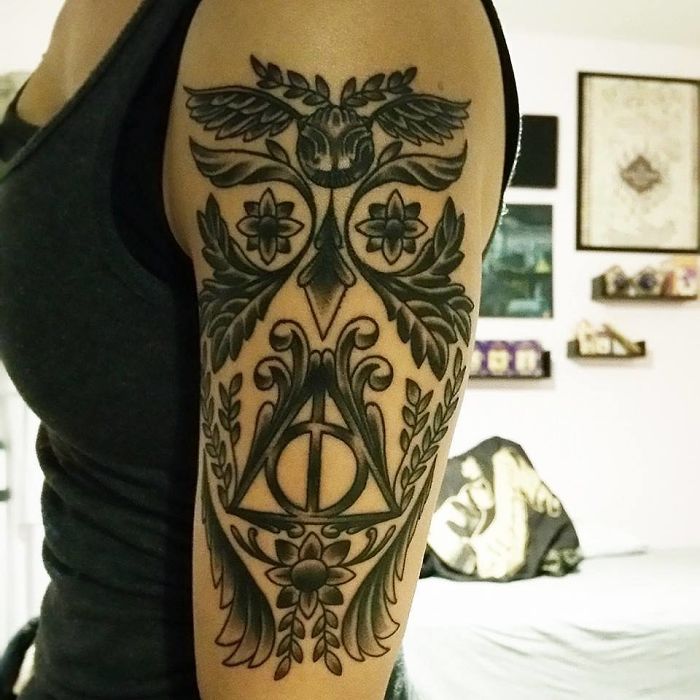 Harry Potter tattoo featuring the Deathly Hallows symbol with intricate floral and owl designs on a person's upper arm.
