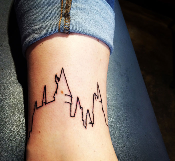 A minimalist Harry Potter tattoo depicting the Hogwarts skyline on a person's leg.