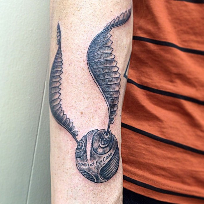 Golden Snitch tattoo with detailed wings on a forearm, capturing Harry Potter magic.