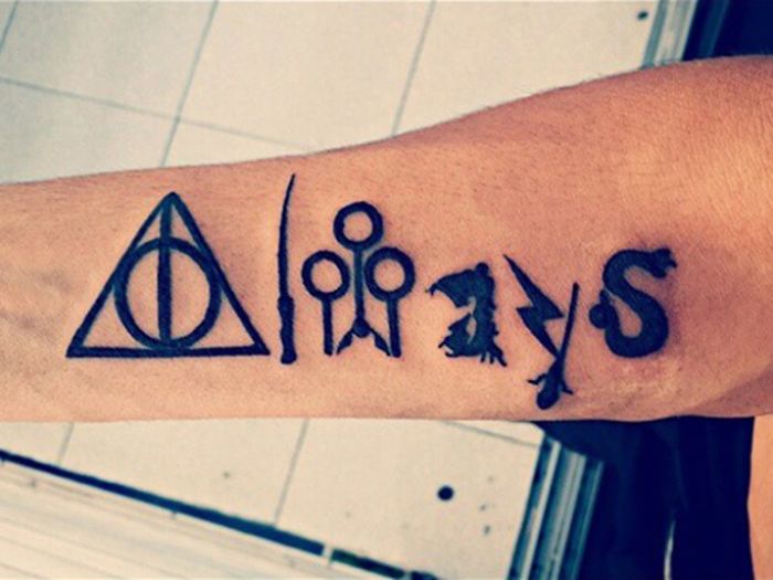 Harry Potter tattoo featuring symbols like the Deathly Hallows, wand, and broomstick on a forearm.