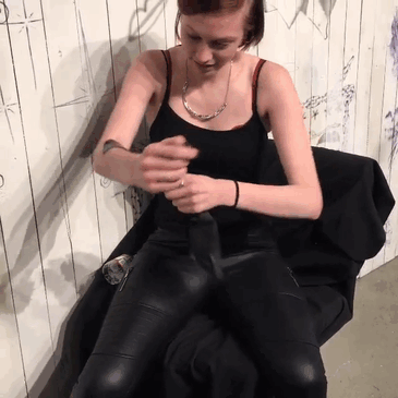 Person participating in a surprise tattoo event, preparing to put their arm through a hole as part of an artistic experience.