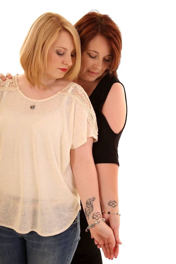 Mother and daughter showing matching tattoos symbolizing their unbreakable bond.