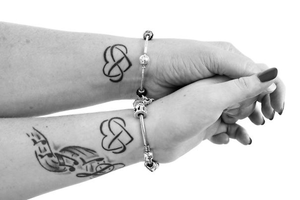 Mother-daughter tattoos featuring intertwined hearts, symbolizing unbreakable bond, with matching bracelets.