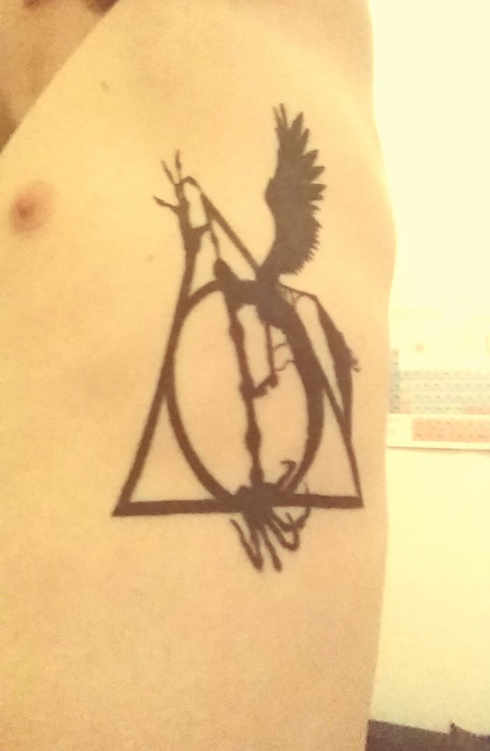 Harry Potter tattoo featuring the Deathly Hallows symbol with a phoenix design on skin.