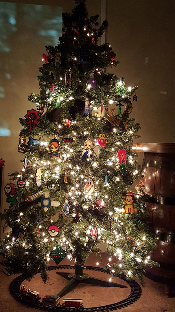 Cat perched in a decorated Christmas tree, surrounded by lights and ornaments.