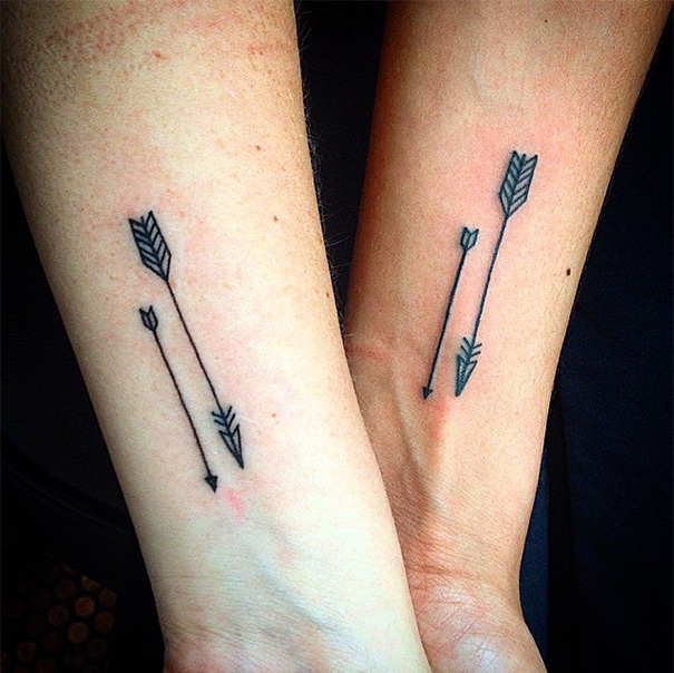 Matching arrow tattoos on forearms symbolize mother-daughter bond.