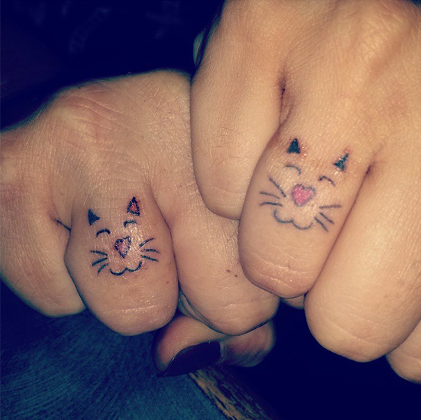 Mother-daughter cat face tattoos on knuckles, symbolizing their unbreakable bond.