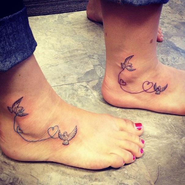 Mother-daughter tattoos of birds and hearts symbolizing an unbreakable bond on feet.