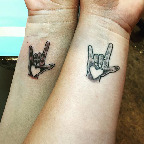 Matching mother-daughter tattoos featuring hands with heart designs.