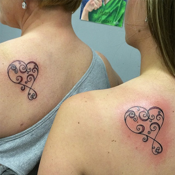Mother-daughter matching heart tattoos with swirls on their shoulders, symbolizing unbreakable bond.