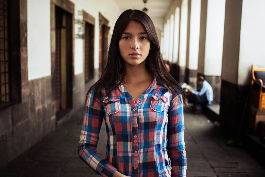 Woman in plaid shirt standing in corridor, captured by Romanian photographer showcasing global beauty.