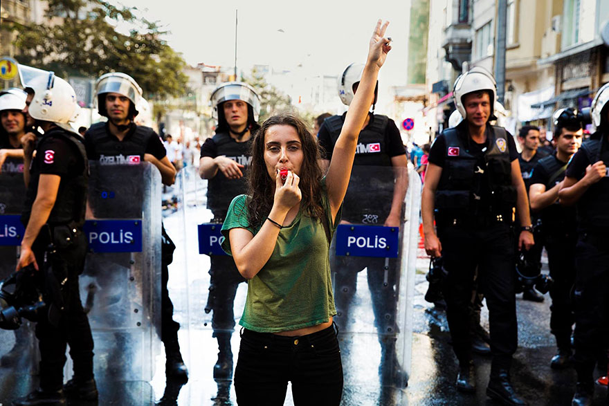 Woman protests with whistle in front of police, highlighting beauty and diversity captured by Romanian photographer.