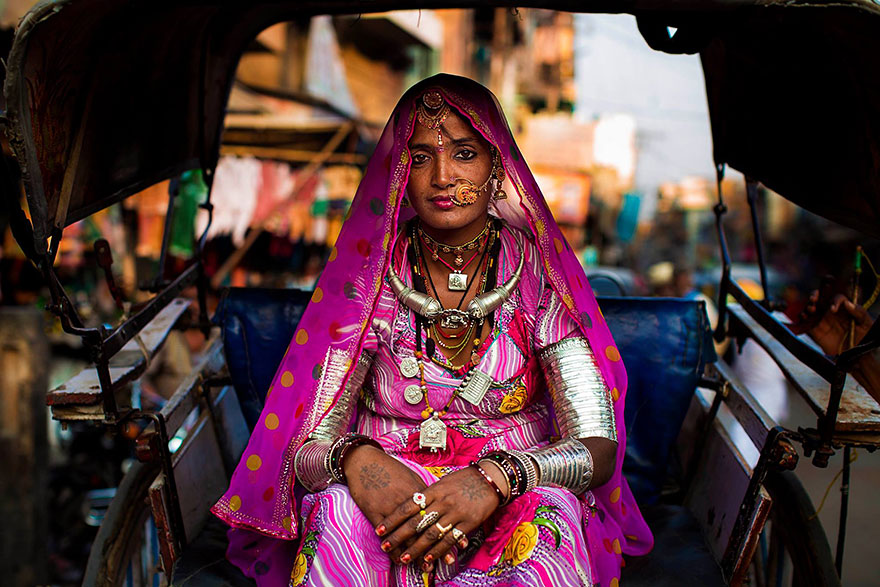 Woman in vibrant traditional attire sits in a rickshaw, showcasing global beauty photography.