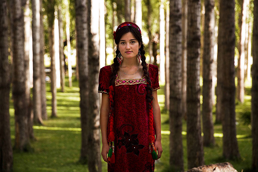Woman in red dress in forest, photographed by Romanian photographer showcasing beauty from diverse cultures.
