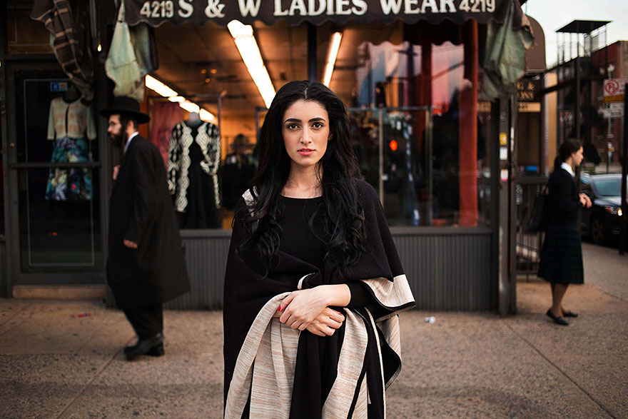Woman in black dress outside a clothing shop, showcasing diverse beauty, photographed by a Romanian photographer.