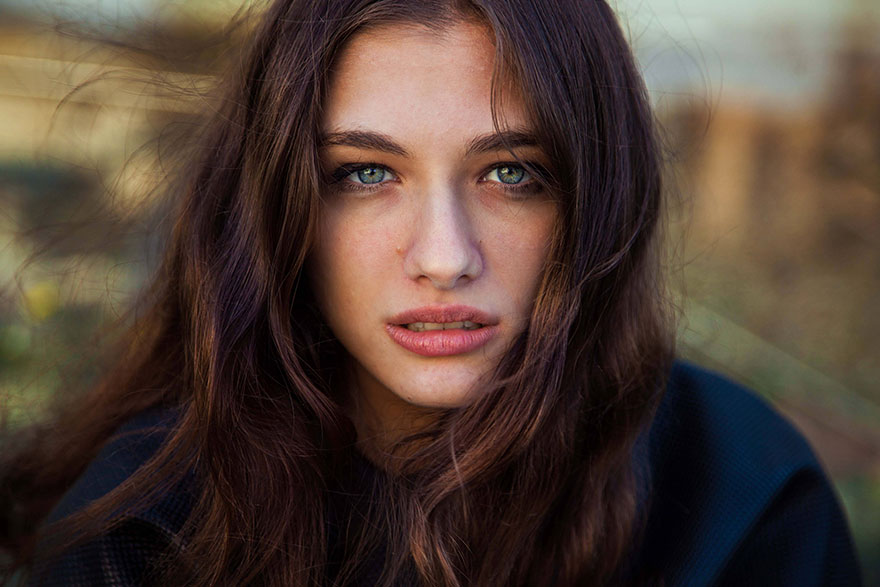 Young woman with long brown hair and blue eyes, captured by Romanian photographer highlighting diverse beauty.