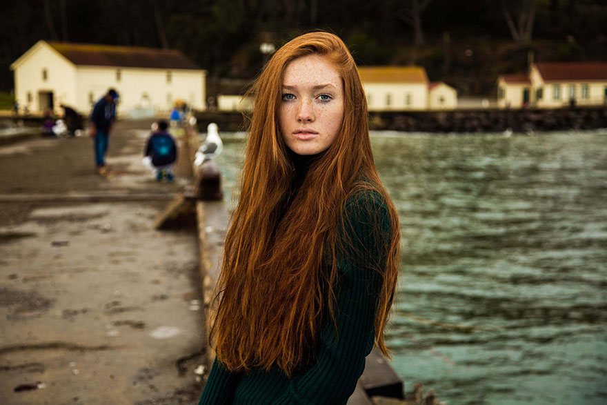 Romanian photographer captures a woman with long red hair near the water, showcasing diverse beauty.