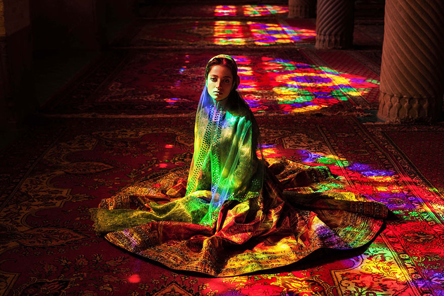 Woman in vibrant traditional attire with colorful light reflections by Romanian photographer, showcasing global beauty.