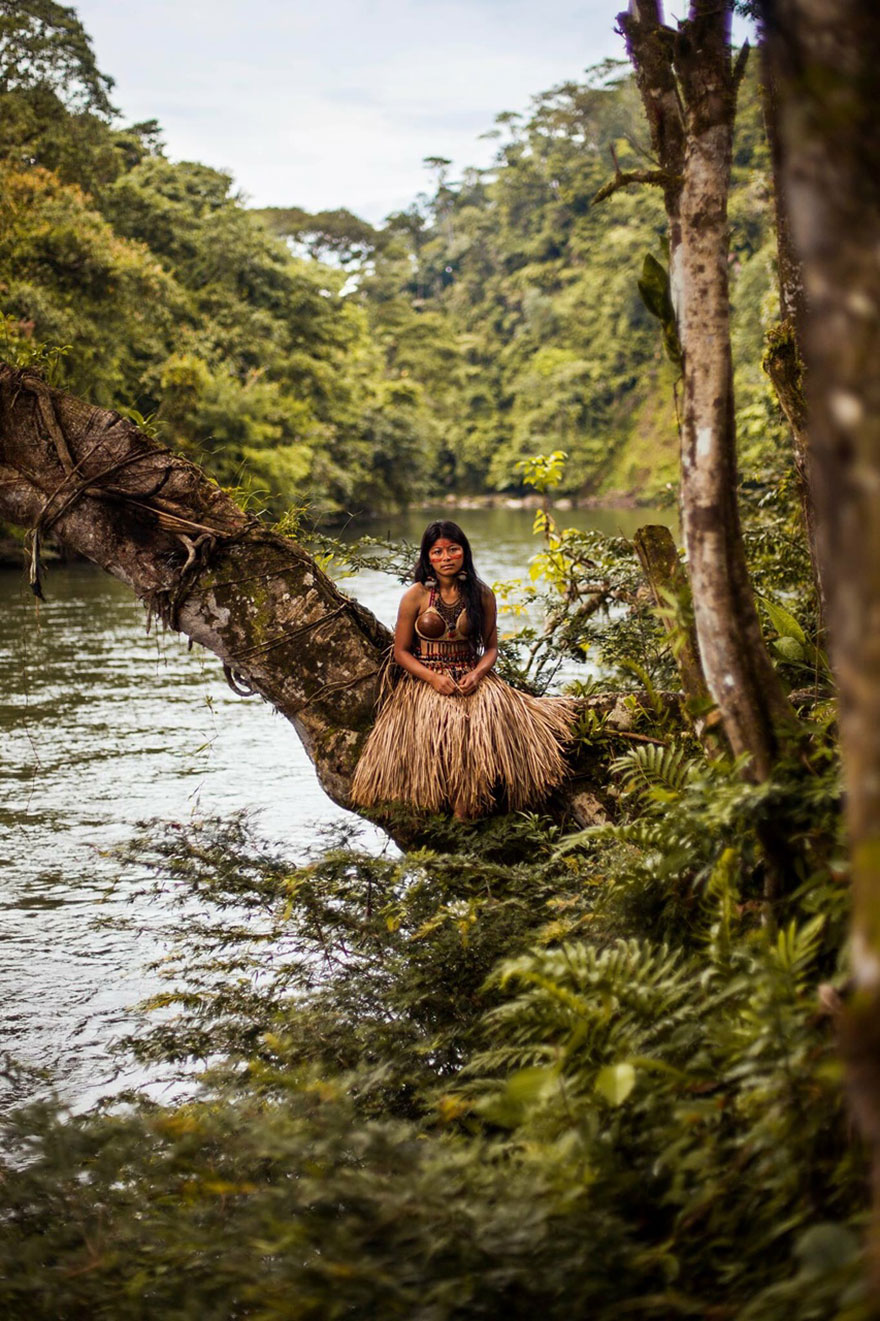 Woman in traditional attire on a tree by a river, captured by Romanian photographer, showcasing global beauty.