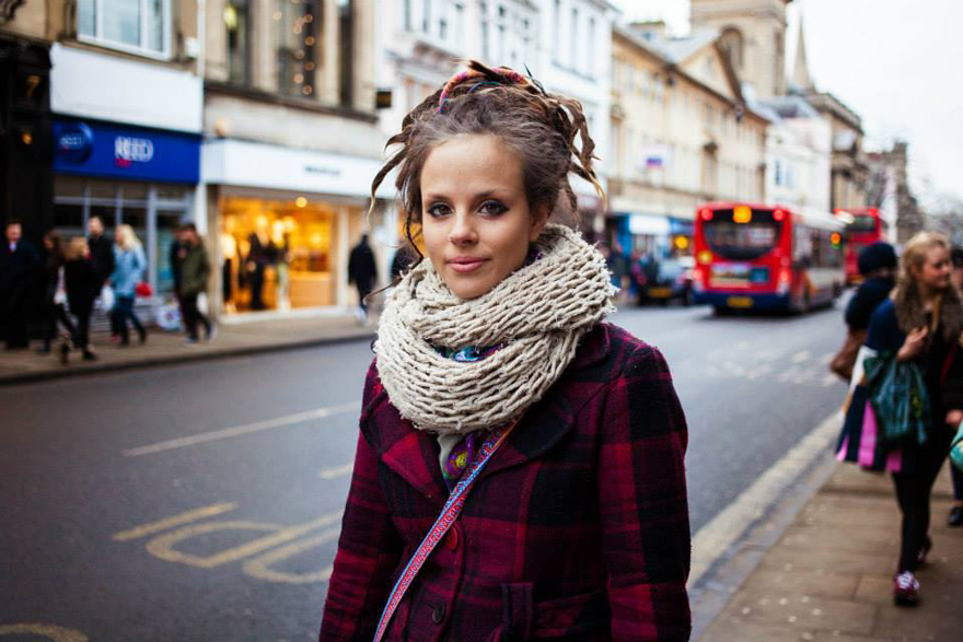 Woman in a plaid coat and scarf on a busy street, part of a beauty photography project by a Romanian photographer.