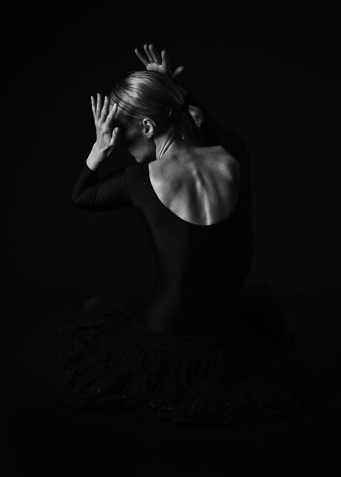 Ballet dancer in a black tutu posing gracefully in dramatic lighting, highlighting the art of ballet.