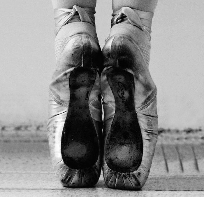 Close-up of worn ballet pointe shoes highlighting the cost of applause in ballet.