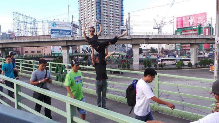 Ballet dancer performing a lift on a busy city sidewalk, highlighting the art and cost of applause in urban settings.