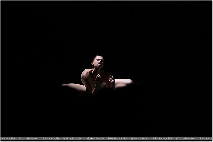 Dancer performing ballet on stage, surrounded by darkness, focusing on the art of expression and movement.