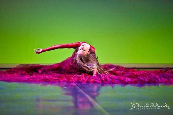 Ballet dancer in a flowing red costume gracefully pose on stage, celebrating Ballet Day.