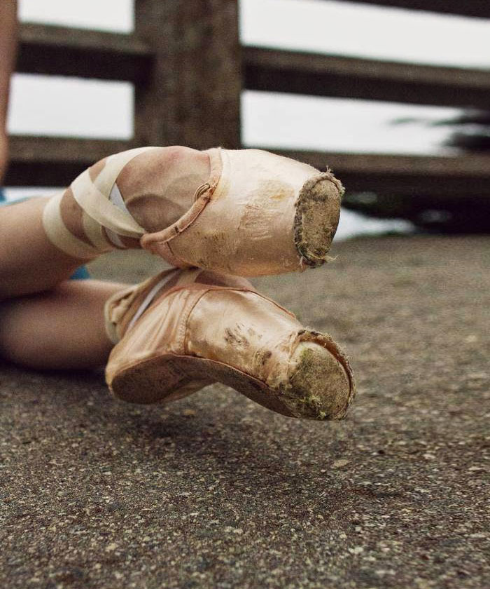 Worn ballet pointe shoes on a rough surface, highlighting the dedication and cost of applause in ballet.