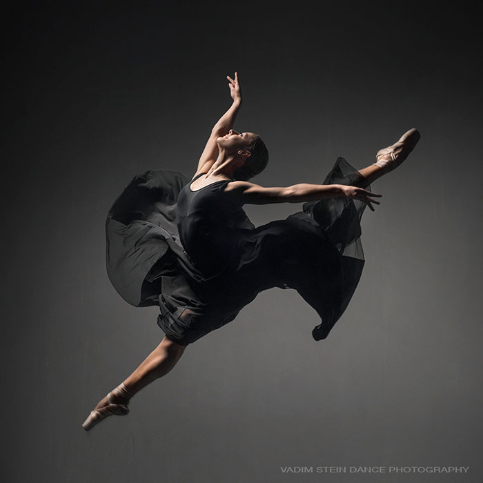 Ballet dancer in a graceful leap wearing a black costume, showcasing the art, elegance, and discipline of ballet.
