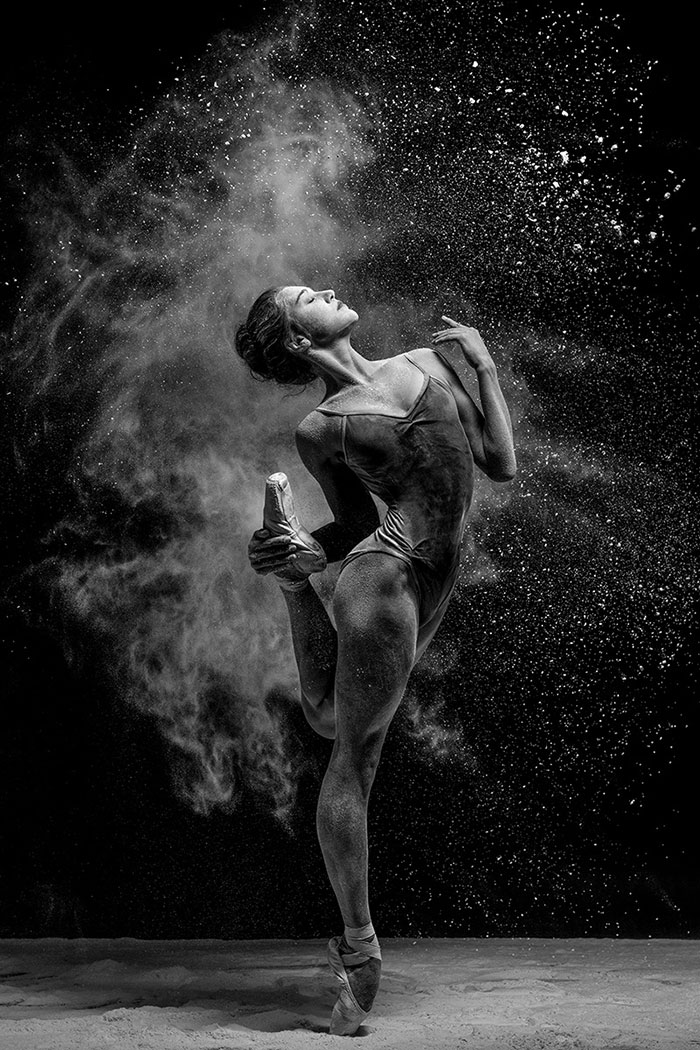 Ballet dancer striking a graceful pose with powder flying around, celebrating Ballet Day.