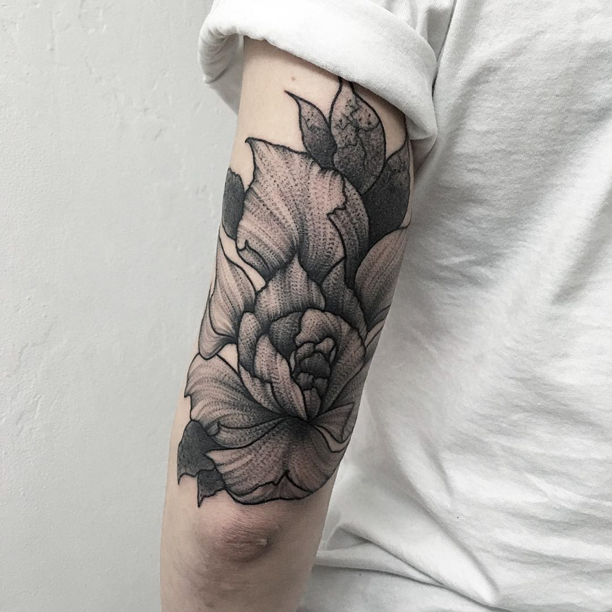 Black and grey floral tattoo on forearm, showcasing intricate design typical of Russian artist's style.