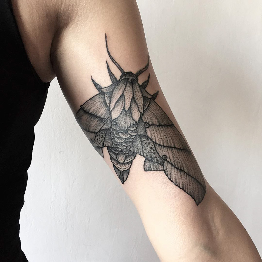 Dark and eerie creature tattoo of a moth on an arm, designed by Russian artist.