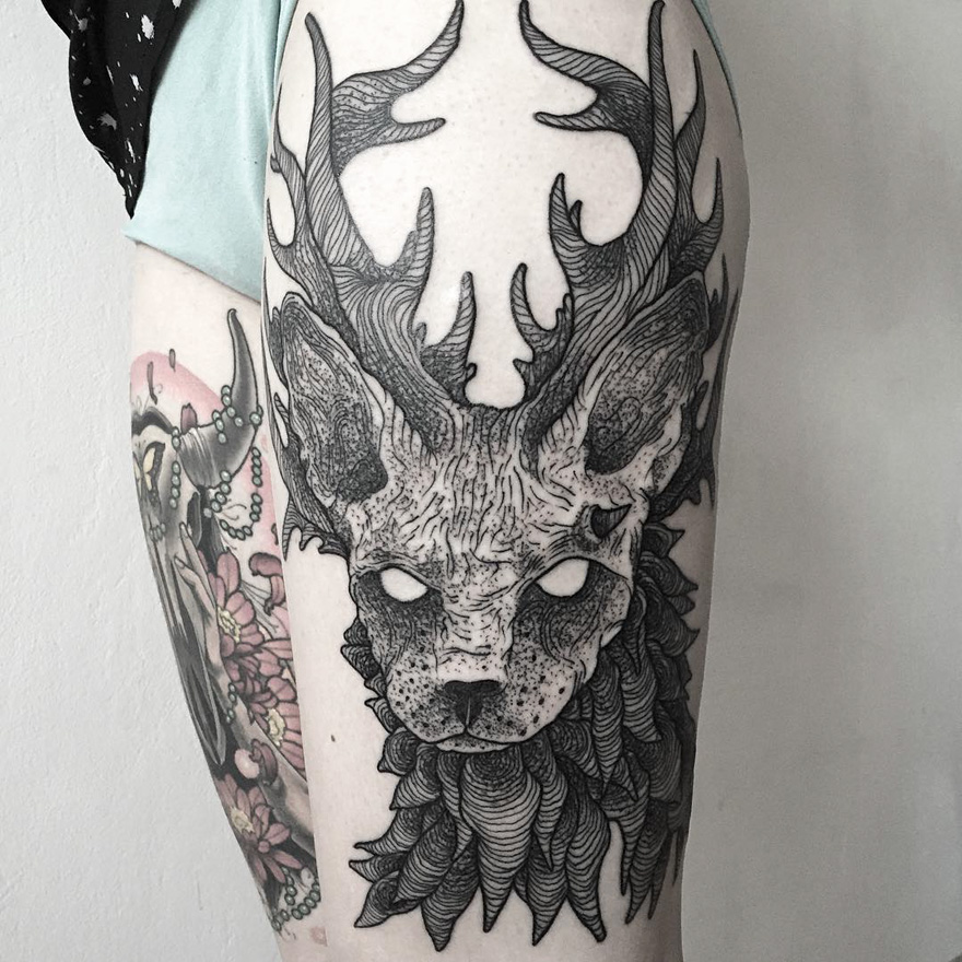 Tattoo of an eerie creature with antlers by Russian artist on a person's arm, showcasing intricate dark details.