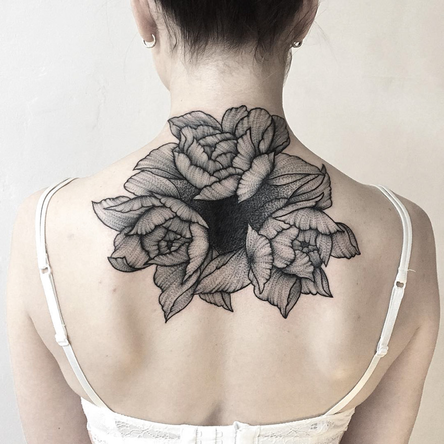 Intricate floral tattoo on upper back; dark and eerie style by Russian artist.
