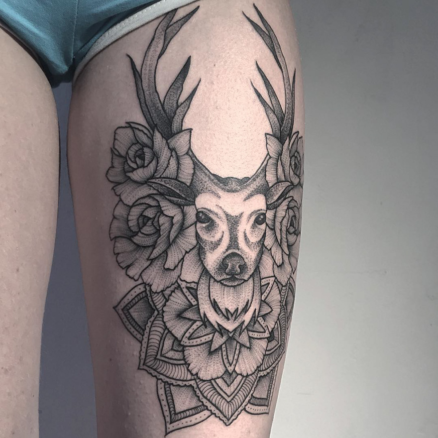 Tattoo of an eerie creature with antlers and floral elements by a Russian artist on a person's thigh.