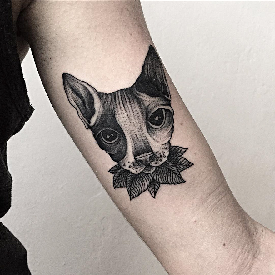 Tattoo of a cat with dark, eerie features on an arm by a Russian artist.