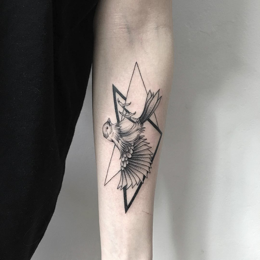 Tattoo of an eerie creature on arm by Russian artist, featuring geometric shapes.