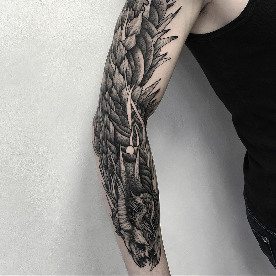 Arm with dark eerie creature tattoo by Russian artist, featuring intricate details and shading on a sleeveless canvas.