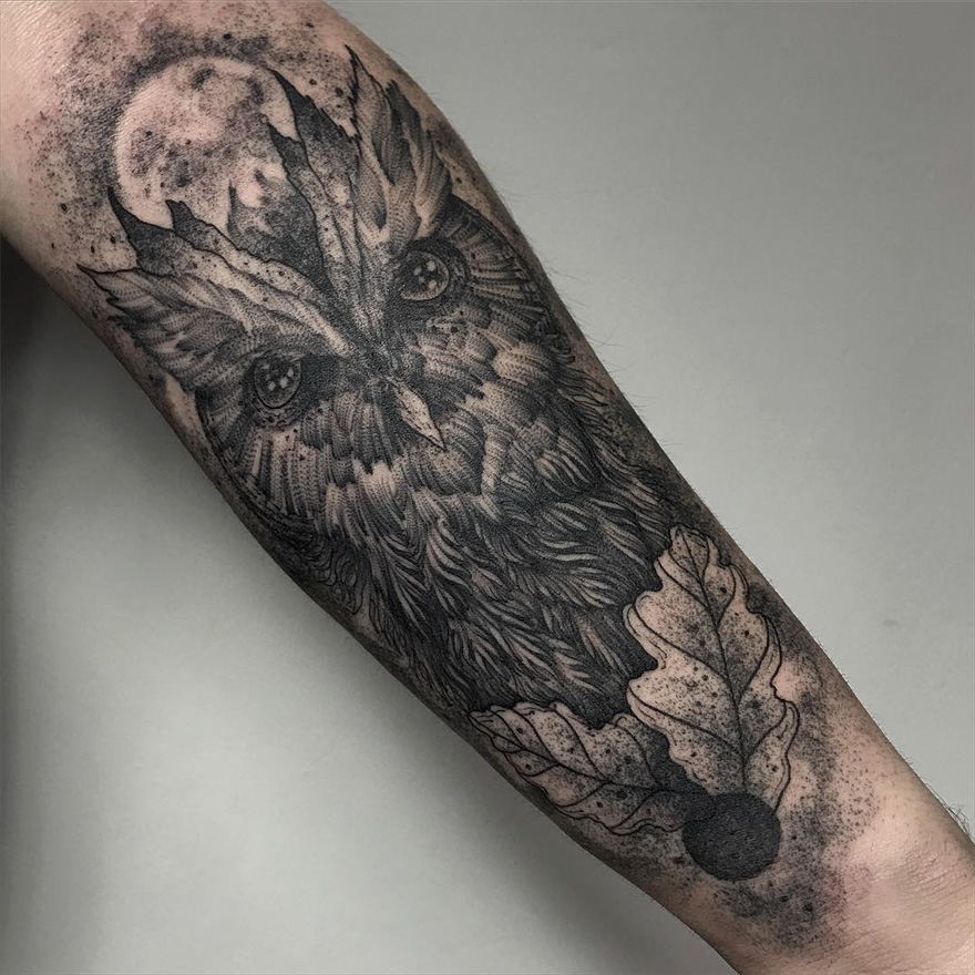 Dark creature tattoo of an owl with oak leaves on arm, designed by a Russian artist.